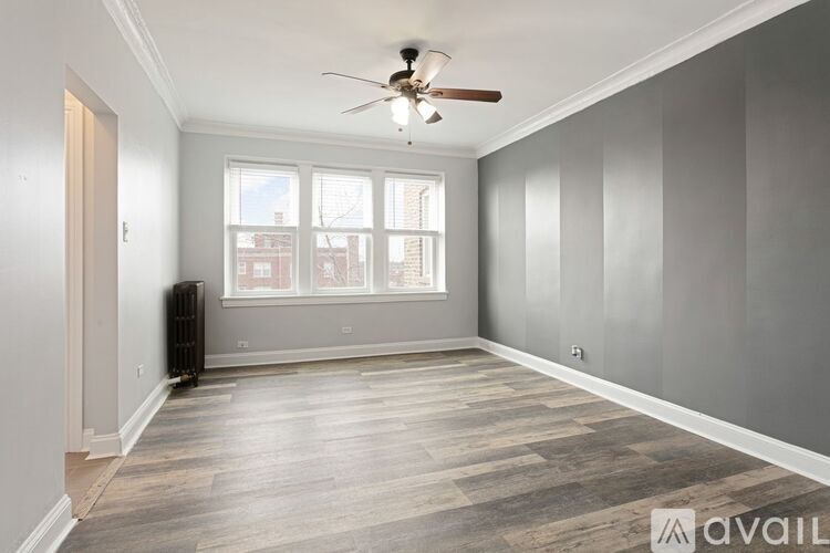 A room with a ceiling fan and a window overlooking a cityscape.