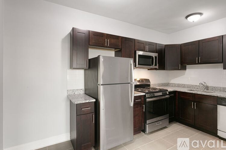 A kitchen with a refrigerator, microwave, oven, and sink.