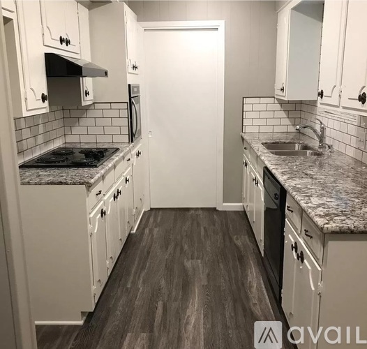 A kitchen with white cabinets and a black stove top.