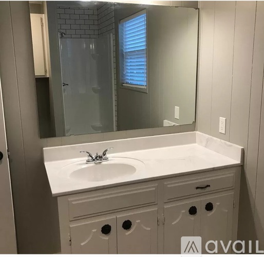 A white bathroom vanity with a sink and a mirror.