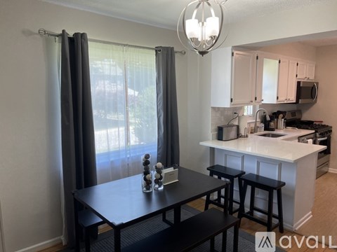 A kitchen with a table and chairs in front of a window with curtains.