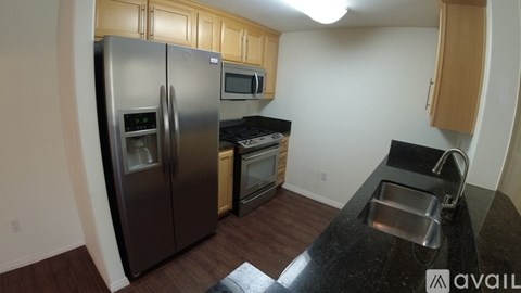 A kitchen with a black counter top and stainless steel appliances.