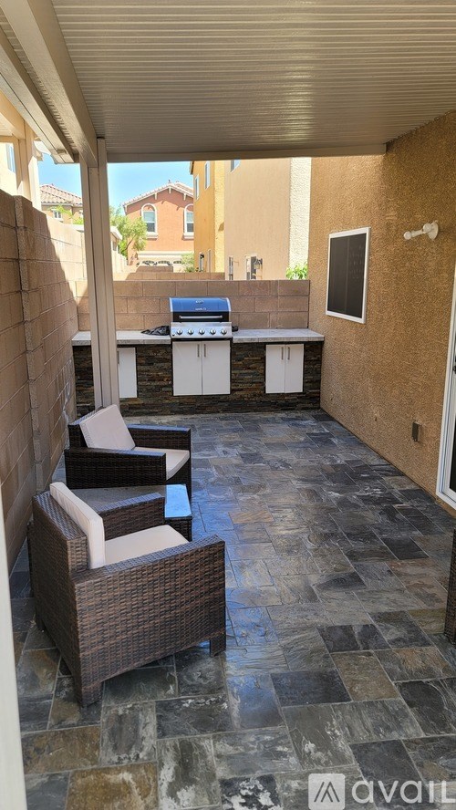 A patio with a BBQ and chairs.
