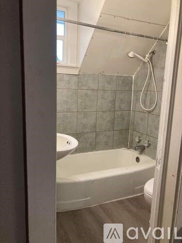 A bathroom with a white tub and a window.