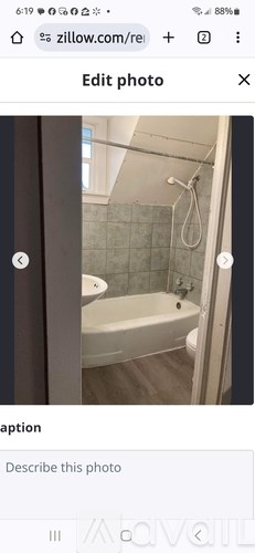 A white bathtub in a bathroom with grey tiles.