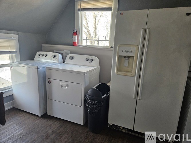 A kitchen with white appliances and a black trash can.