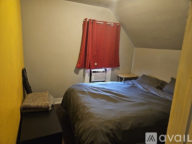 A bedroom with a bed, a chair, and a table.