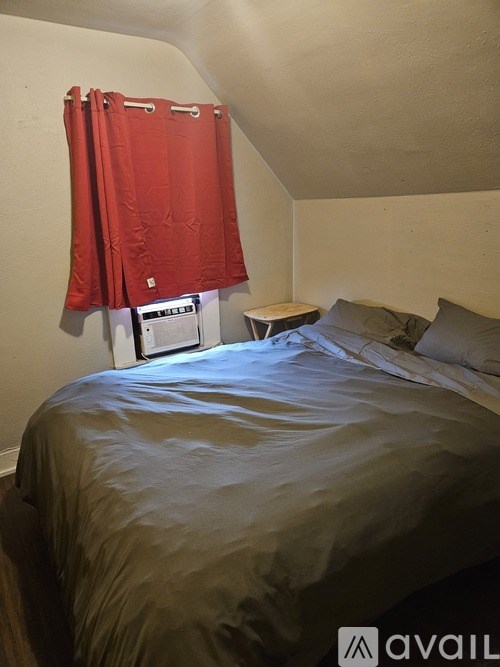 A bedroom with a bed, a small table, and a red curtain.