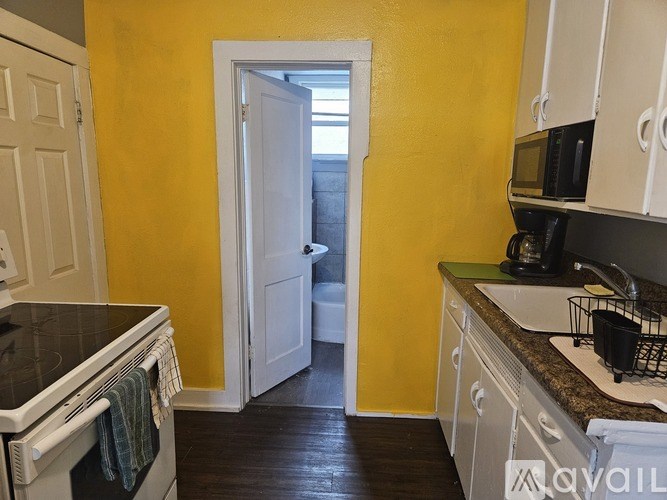 A kitchen with yellow walls and white cabinets.
