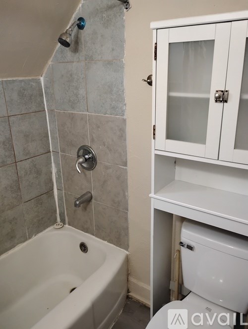 A kitchen with a table and chairs in the foreground and a bed in the background.