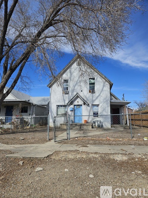 A small bedroom with a bed, a small table, and a red curtain.