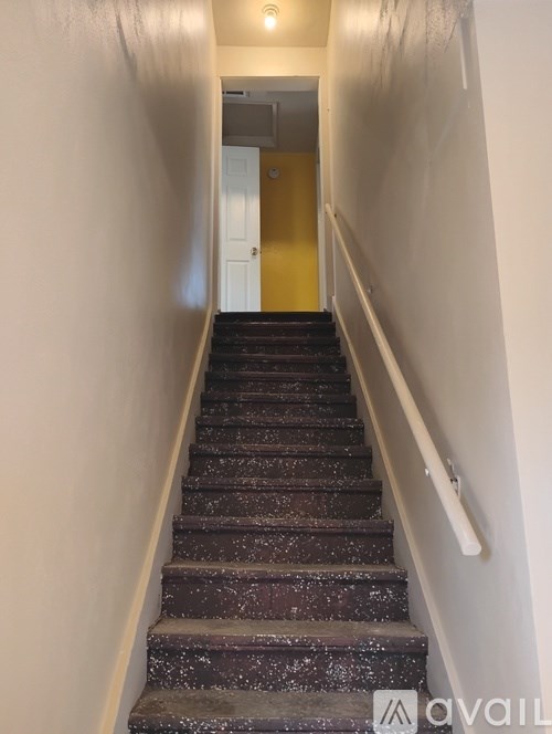A staircase with a white railing and a yellow door at the top.