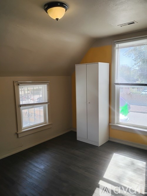 A room with a white cabinet and a window with blinds.