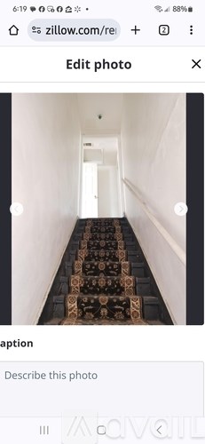 A long hallway with a patterned carpet leads to a door at the end.