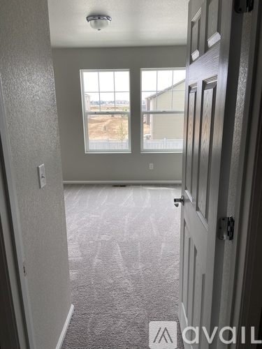 A carpeted hallway with a door leading to a balcony.