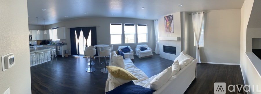 A living room with a white couch and a kitchen area in the background.