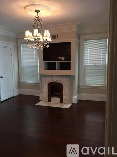 A chandelier hangs over a fireplace in a room with hardwood floors.