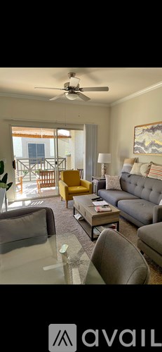 A living room with a glass table and a grey couch.