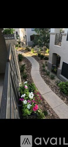 A narrow alley with a concrete path and a metal railing on the left side.