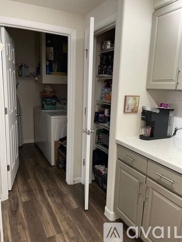 A kitchen with a white fridge and cabinets, a white counter top, and a white washing machine.