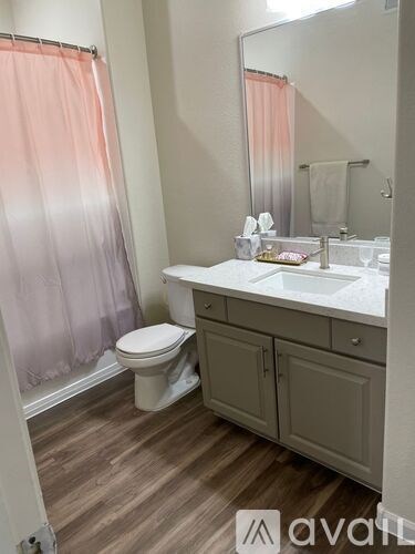 A bathroom with a toilet, sink, and shower curtain.