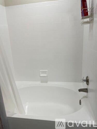 A white bathtub with a shower head and faucet.