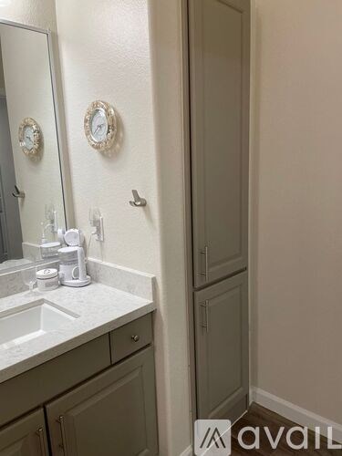A bathroom with a sink, mirror, and cabinets.