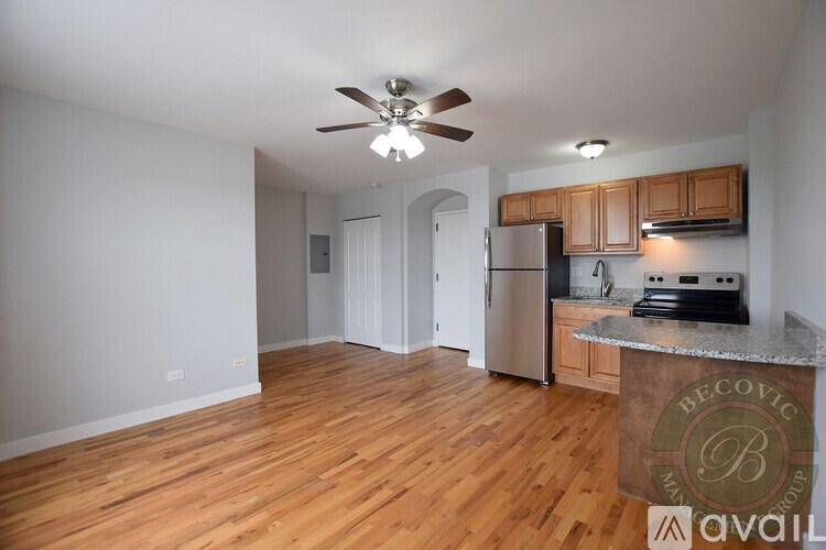 A kitchen with wooden floors and a ceiling fan.