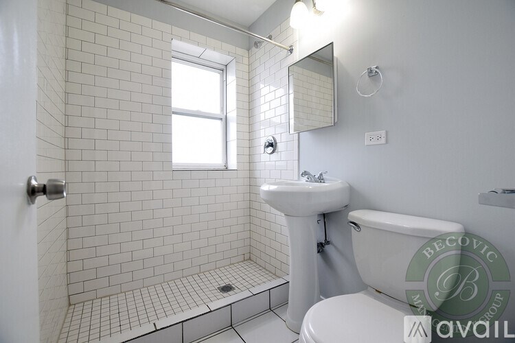 A white bathroom with a sink, toilet, and shower.