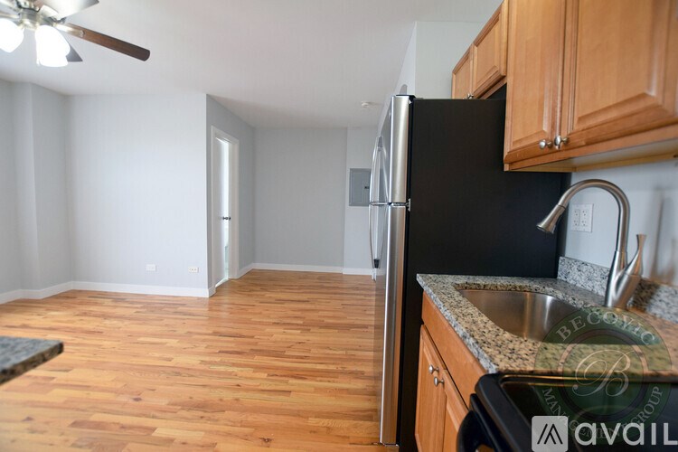A kitchen with a black fridge and wooden floors.