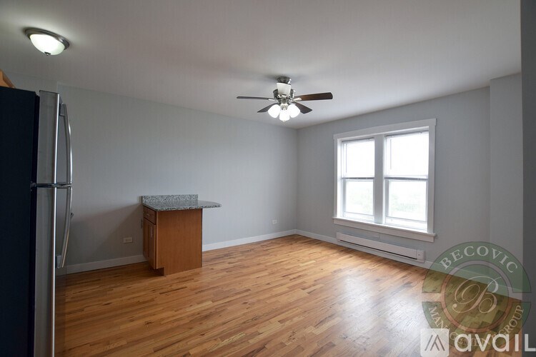 A room with a wooden floor, a ceiling fan, and a window with blinds.