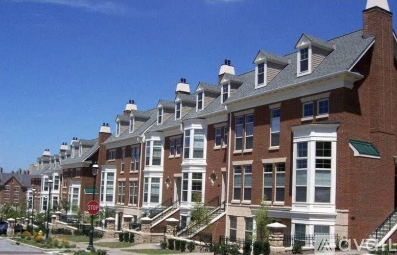 A row of red brick houses with white trim and a stop sign in front of the first house.