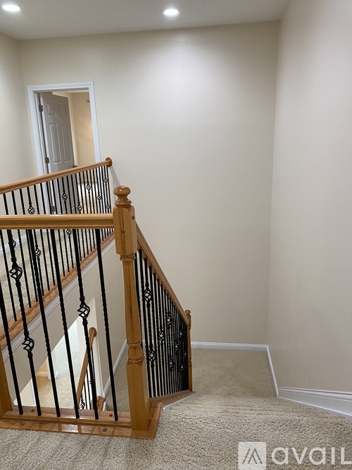 A wooden staircase with a black railing.