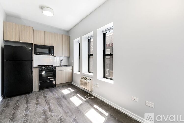 A kitchen with black appliances and a wooden cabinet.