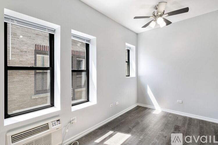 A room with a ceiling fan and two windows.
