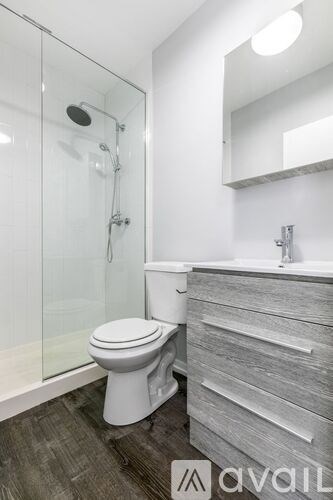 A modern bathroom with a white toilet and a glass shower stall.