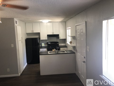 A kitchen with white cabinets and a black fridge.