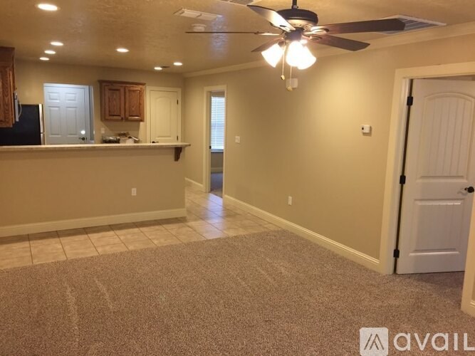 A spacious room with a ceiling fan and carpeted floor.