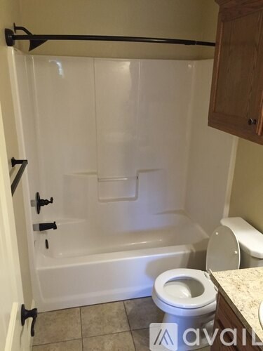 A bathroom with a toilet, tub, and cabinet.