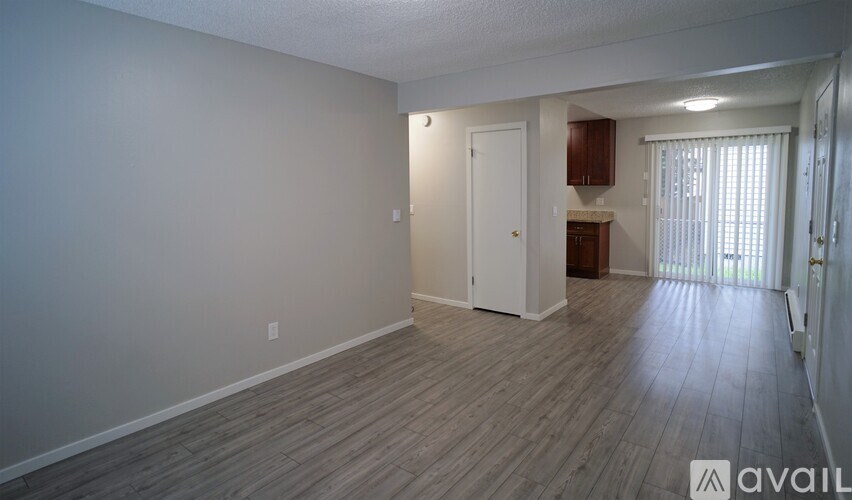 A spacious room with wooden flooring and white walls.