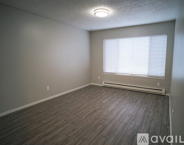 A room with wooden flooring and a window with blinds.