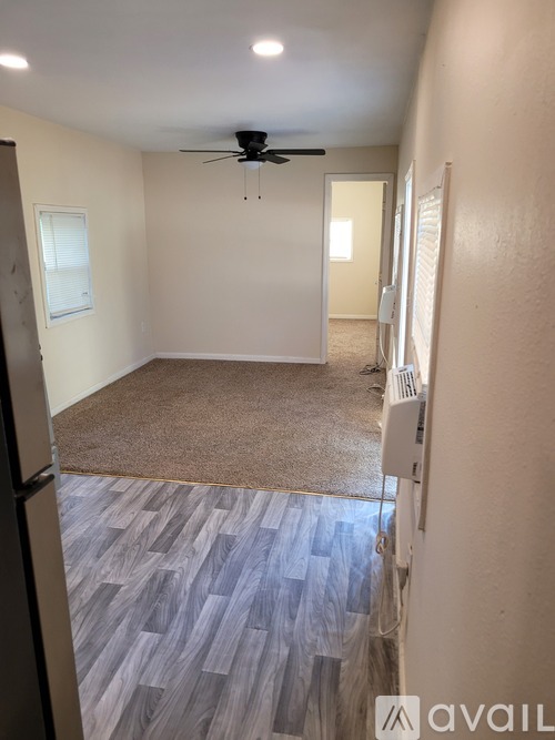 A room with a ceiling fan and a door leading to another room.