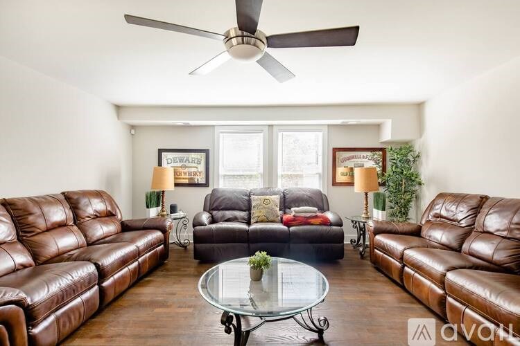A living room with brown leather couches and a glass coffee table.