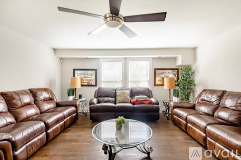 A living room with brown leather couches and a glass coffee table.