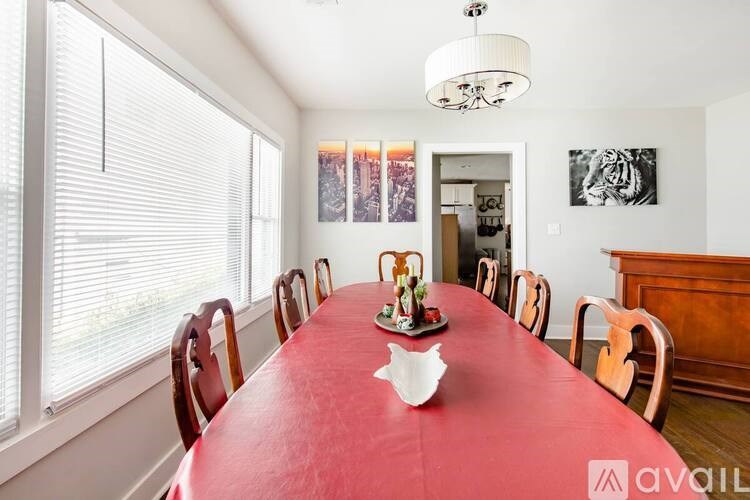 A long red table is surrounded by chairs in a white room.
