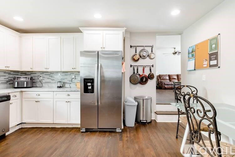 A kitchen with a stainless steel refrigerator and white cabinets.