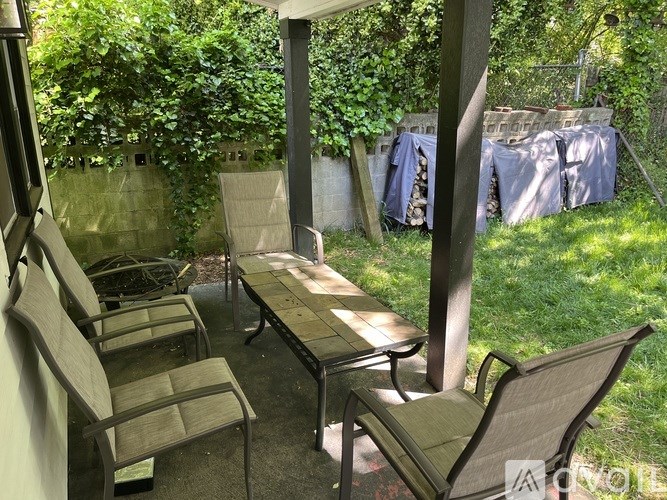 A patio with a table and chairs is surrounded by greenery.