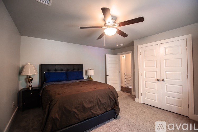 A bedroom with a bed, a ceiling fan, and a door.