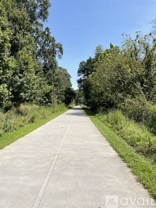 A concrete pathway leads through a green, leafy area.