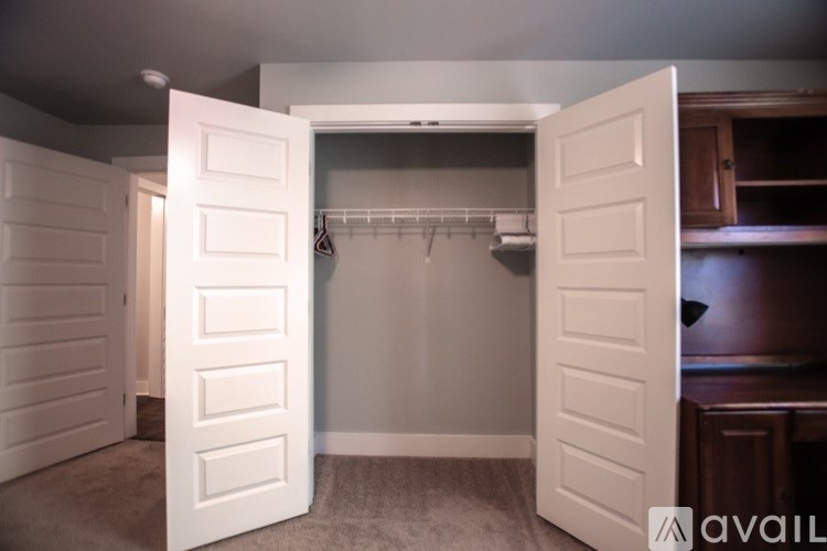A white door is open to a room with a coat rack.